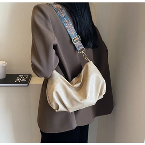 Detail of beige pleated dumpling bag with vintage ethnic embroidery wide shoulder strap