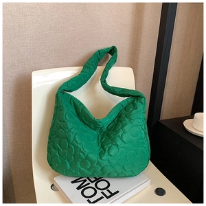 Detail of green quilted bucket bag with 3D floral texture and soft nylon fabric