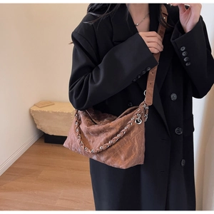 Detail of vintage brown quilted leather crossbody bag with metallic woven chain strap