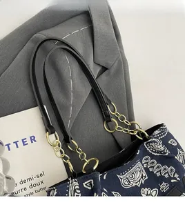 Detail of navy paisley canvas tote bag with black leather and gold metal chain strap