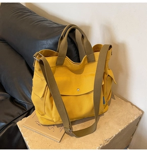 Detail of yellow canvas tote bag with magnetic front pocket and adjustable green strap