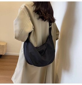 Detailed view of black nylon crescent bag worn crossbody with adjustable wide strap