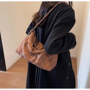 Brown quilted chain shoulder bag shown on model for size and soft texture detail