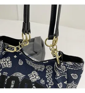 Detail of navy canvas tote with bandana print, black leather straps and gold chain hardware