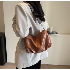 Detail view of the brown retro pleated hobo bag with ethnic geometric woven strap