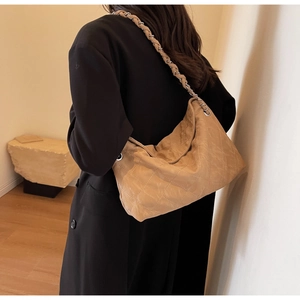 Detailed view of quilted leather texture and woven chain strap on khaki shoulder bag