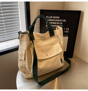Detail of canvas tote bag with contrast green handles and large functional snap pocket