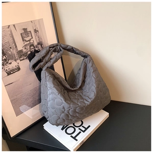 Detail of grey quilted bucket bag with cloud stitching pattern and wide strap