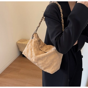 Close-up of beige quilted leather hobo bag with classic chain strap on model