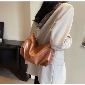 Close-up of retro brown pleated bag with vintage ethnic embroidery wide shoulder strap
