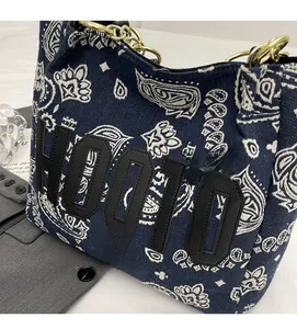 Close-up of navy canvas tote bag featuring white paisley print and HOOTO leather appliqué