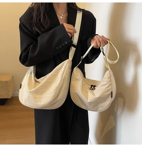Close-up of large and small beige nylon crescent bags with adjustable straps