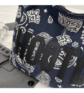 Detailed view of paisley canvas tote bag with black leather letter patch embroidery