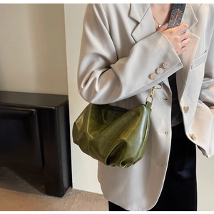 Detail of olive green ruched dumpling bag with vintage texture and embroidered wide strap