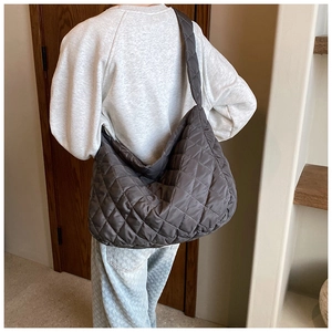 Rear view of a model wearing the large quilted oxford bucket bag in taupe with wide strap