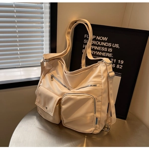 Detail der cremeweißen Nylontasche mit Funktionstaschen und verstellbarer Metallschnalle