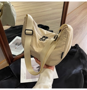 Detail of adjustable wide shoulder strap and nylon fabric texture on beige bag