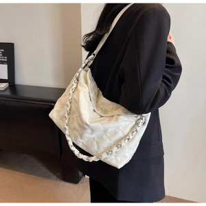 Detail of white quilted rhombus pattern on leather hobo bag with woven chain strap