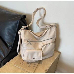 Detailansicht der cremefarbenen Nylontasche mit Reißverschlusstaschen und Gurt