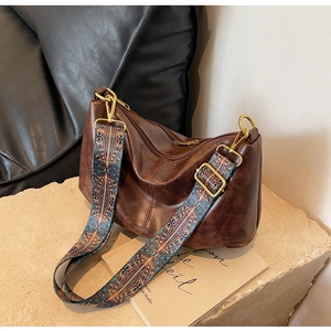 Detail of dark brown leather crossbody bag with colorful geometric woven wide strap