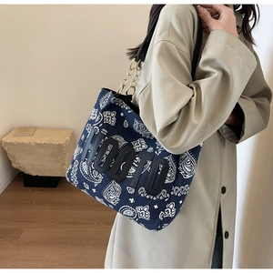 Detail of navy paisley canvas tote bag featuring HOOTO patch and gold chain strap