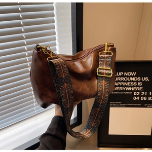 Close-up of brown leather bag with ethnic geometric wide strap and gold hardware