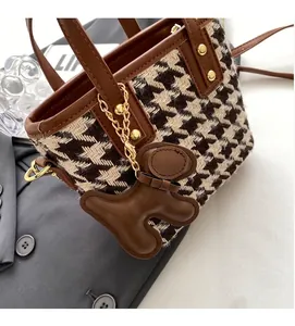 Close-up of houndstooth tote bag with brown leather trim and cute bear charm detail