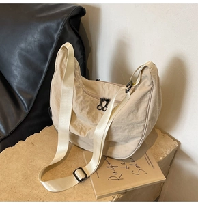 Detail of beige nylon crescent bag featuring double front zippers and wrinkled texture