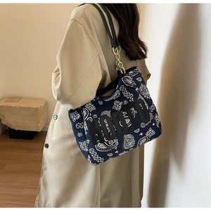 Close-up of navy canvas tote bag with white paisley print and metallic chain detail