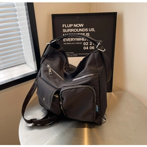 Detail einer schwarzen Nylon-Tasche mit mehreren Reißverschlusstaschen auf Metalltisch
