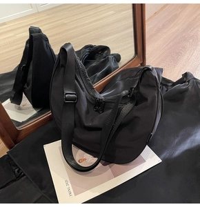 Detail shot of black nylon hobo bag featuring dual zippers and adjustable strap