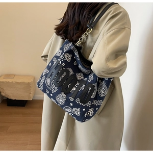 Detail of dark blue paisley canvas tote bag featuring 3D leather HOOTO letters and chain strap