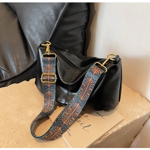 Detail of black leather hobo bag featuring a wide ethnic geometric pattern shoulder strap