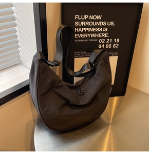 Detail of black nylon half-moon crossbody bag featuring dual zippers and adjustable strap