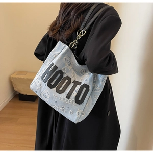 Detail of blue denim tote bag with paisley pattern and black HOOTO letter patch