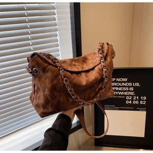Detail of vintage brown quilted bag featuring chain-woven strap and aged leather texture