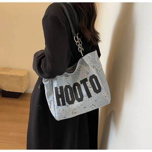 Detail of light blue paisley tote bag with black HOOTO lettering and gold chain strap