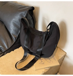 Close-up of black nylon crescent bag featuring adjustable strap on a stone display