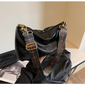 Detail of black crossbody bag with vibrant bohemian woven strap and gold metal hardware