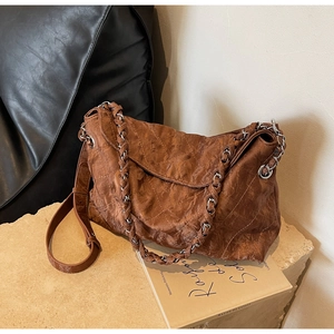 Close-up of vintage brown quilted leather texture and silver chain strap on bag
