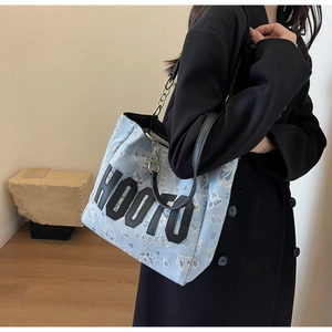 Detail of blue denim tote bag featuring paisley embroidery and HOO70 leather patch