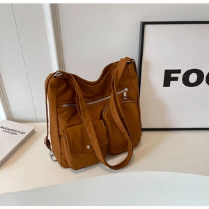 Detailansicht der karamellfarbenen Nylontasche mit mehreren Reißverschlussfächern und Silber