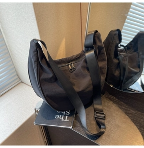 Detail of black nylon crescent bag with double zipper and wide shoulder strap