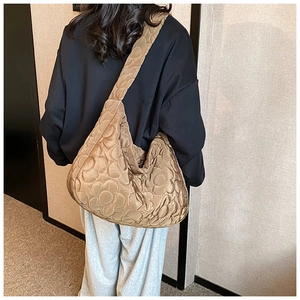 Detailed view of camel quilted nylon shoulder bag with floral stitching on model