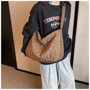 Detailed view of brown quilted hobo bag with floral patterns on a model's shoulder