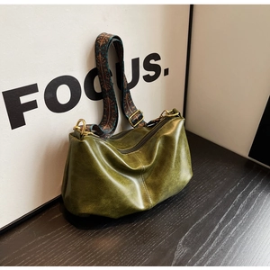 Macro shot of dark green pleated dumpling bag with vintage bronze zippers and wide strap