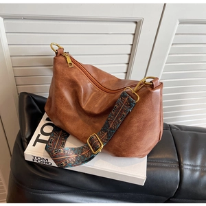 Detailed shot of brown pleated dumpling bag with ethnic style colorful floral wide strap