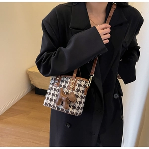 Detail van de mini bucket bag met pied-de-poule patroon, leer en decoratieve hondenhanger