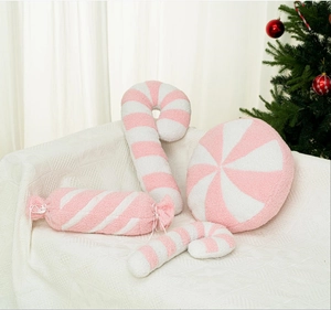 Cuscini di peluche a bastoncino di zucchero rosa e bianco su un divano accogliente