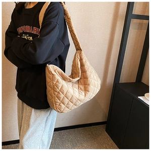 Close-up of quilted crescent shoulder bag featuring diamond stitching and wide strap